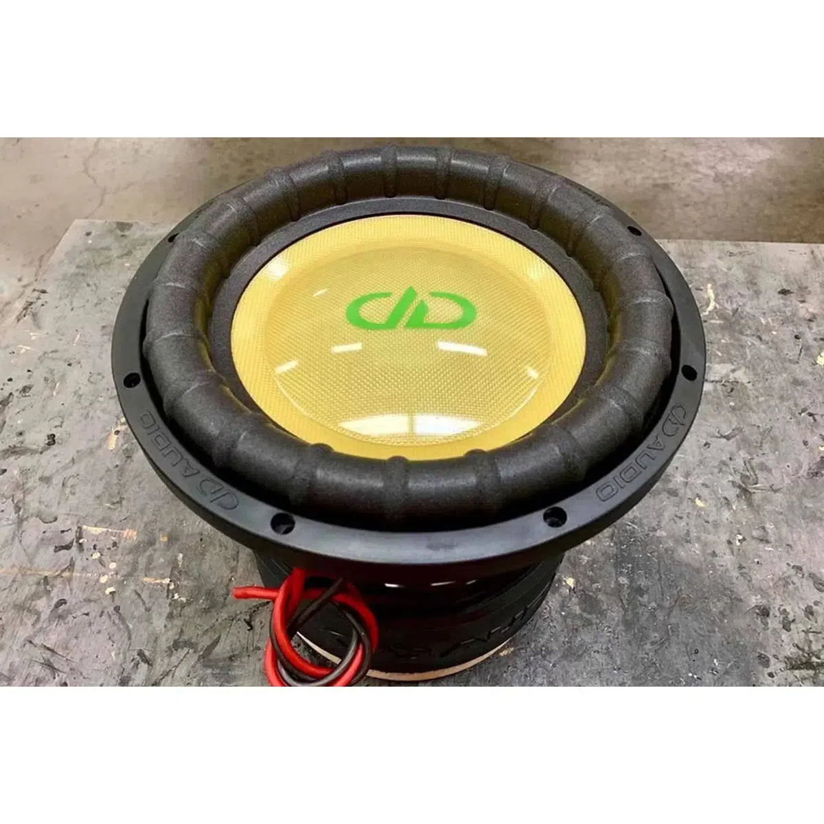 De DD Audio Power Tuned 3512i ESP, een gele 12 subwoofer met zwarte rand, rode draden en groen logo, levert 1200W RMS aan krachtig geluid.