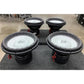 Vier DD Audio Power Tuned 9915b ESP 15 subwoofers met koolstofvezel mengkegels en zwarte frames worden op een grijs tapijt in een werkplaats geplaatst.