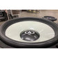 Close-up van de DD Audio Power Tuned 9921b 21-inch subwoofer met zwart-witte conus, middenstuk met koolstofvezelpatroon en ferrietmagneet in een industriële werkplaats.