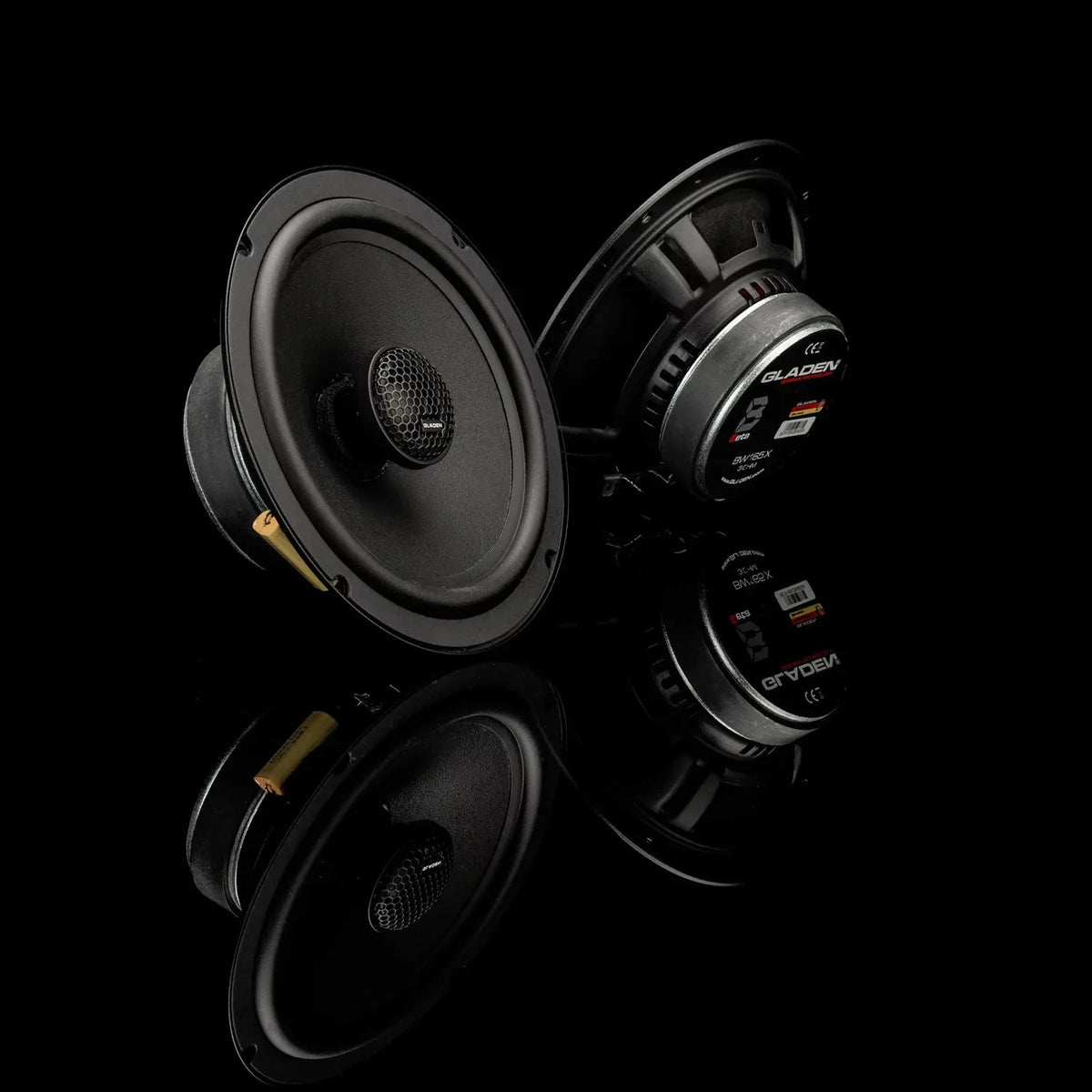 Two Gladen BETA 165-X speakers, 16cm each, are shown front and back with labels visible against a black background.