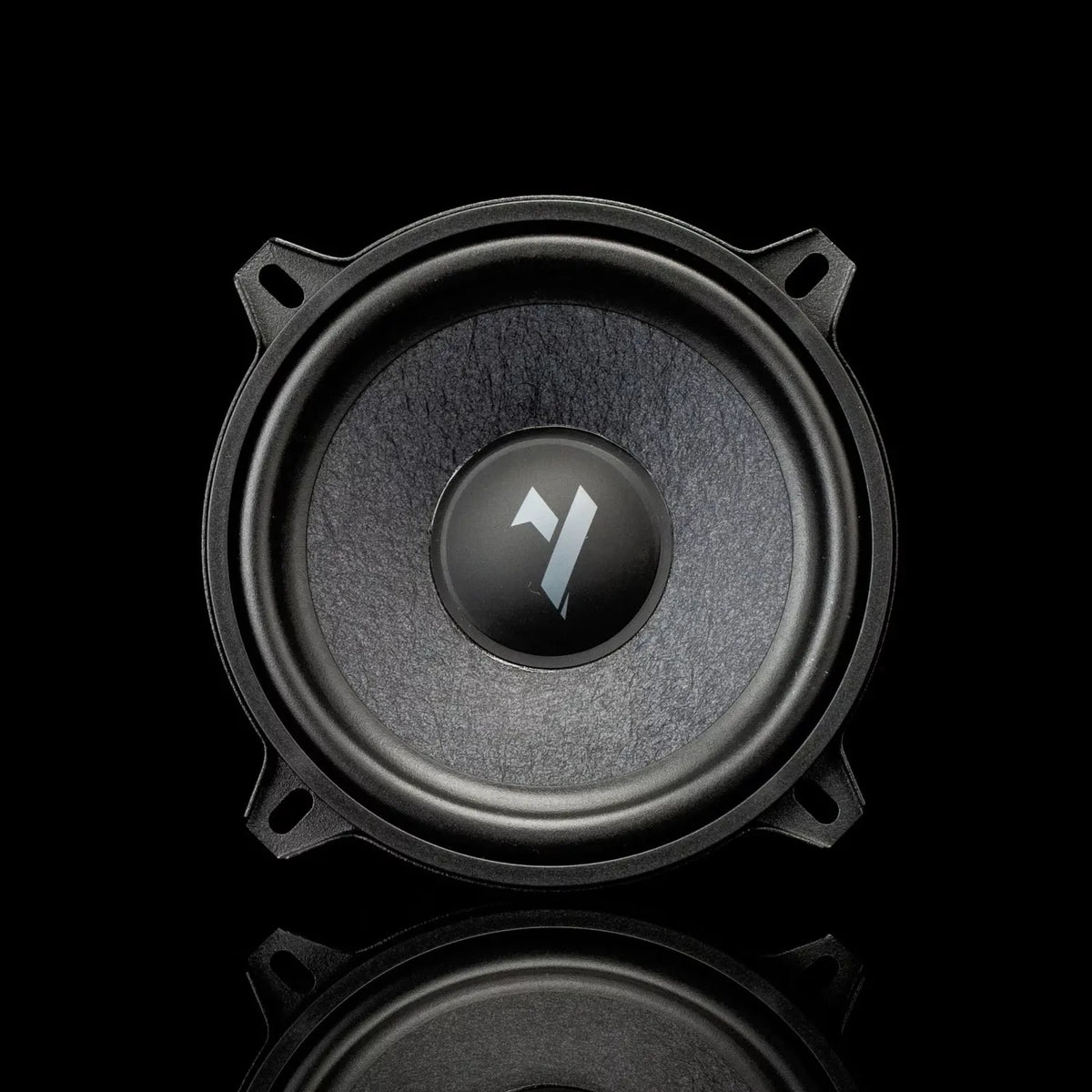 Une enceinte ronde et noire Gladen Gamma 130.2, ornée dun logo argenté en son centre, se détache sur un fond sombre et reflète la qualité sonore exceptionnelle et lélégance du produit.
