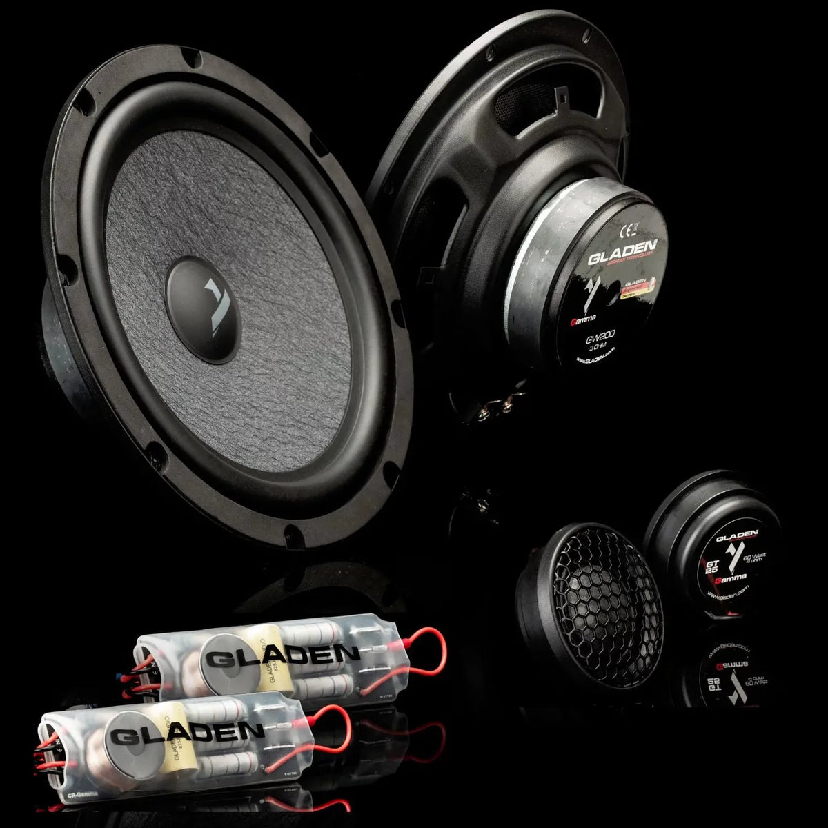 A Gladen Gamma 200.2 AC Lautsprecherset, mit Hochtönern, Frequenzweichen und kräftigem Kickbass, liegt auf spiegelnd schwarzem Untergrund.