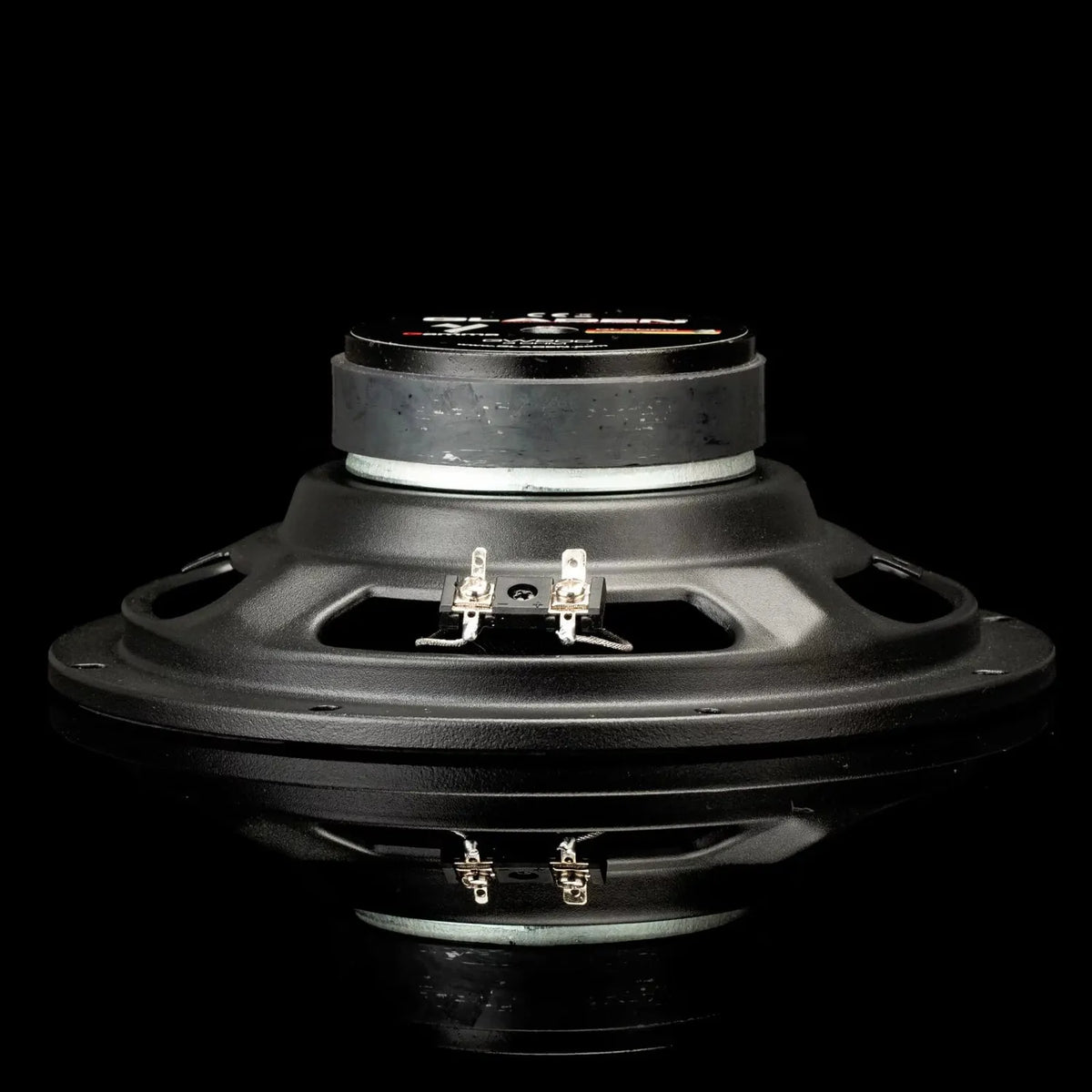 Gladen Gamma 200.2 AC kickbass driver with visible terminals, shown side view on reflective black surface against a black background.