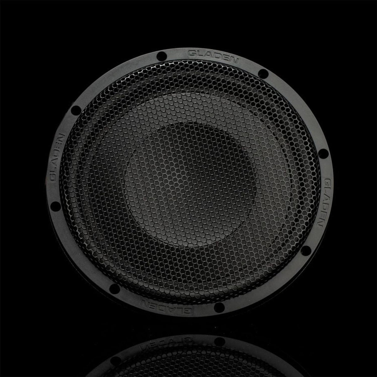 Vue de face : le Gladen GS10-Slim, un caisson de basses rond de 10 pouces, de couleur noire, doté dune grille hexagonale, offre un son puissant sur un fond noir uniforme.