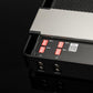 Close-up of the Gladen Mosconi Pro 4|30 AAB EVO amp with red DIP switches, QR code, and two input ports on a glossy black surface.