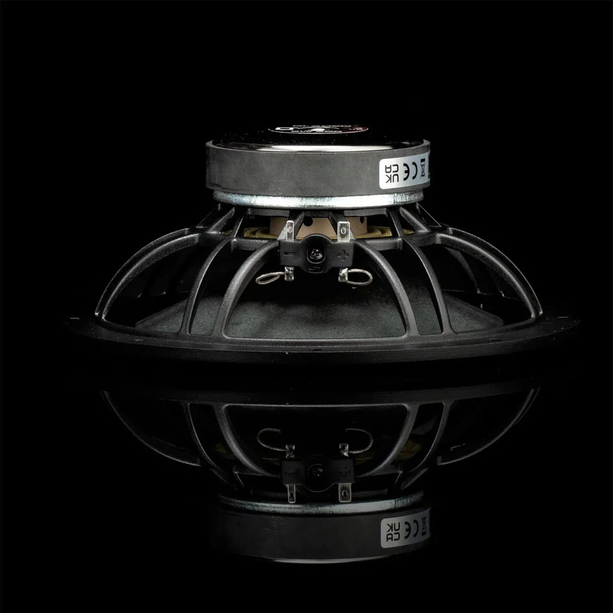 Een Gladen Sigma 200-luidsprekerelement voor car audio, zwart met een metalen frame en aansluitingen, is hier van opzij te zien en wordt weerspiegeld op een glanzend zwart oppervlak.