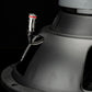 Close-up van een Gladen Sigma SSW12-subwooferaansluiting met een zwart-rood gestreepte kabelstekker tegen een donkere achtergrond.