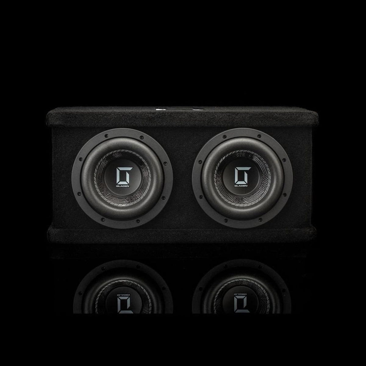 Un cabinet nero e rettangolare per il subwoofer doppio Gladen Sigma SSWX065, dotato di due driver da 6,5 pollici che si riflettono su una superficie lucida.