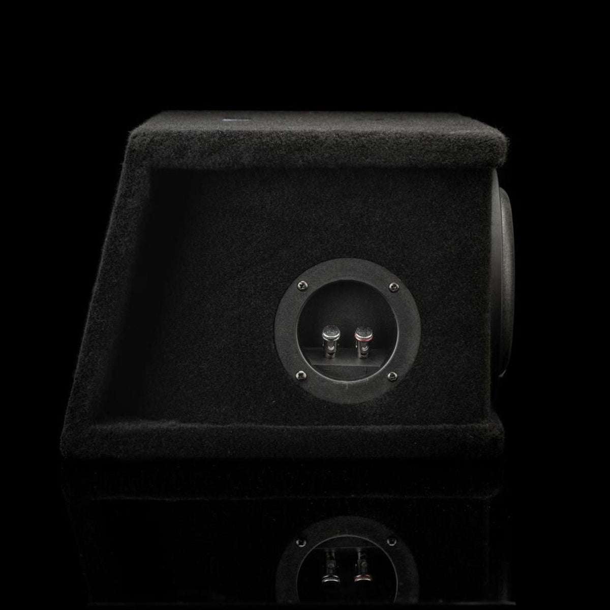 Una cassa per subwoofer Gladen Sigma SSWX065 Dual rivestita in moquette nera, per subwoofer da 6,5, con una piastra terminale rotonda e due terminali, su sfondo nero.