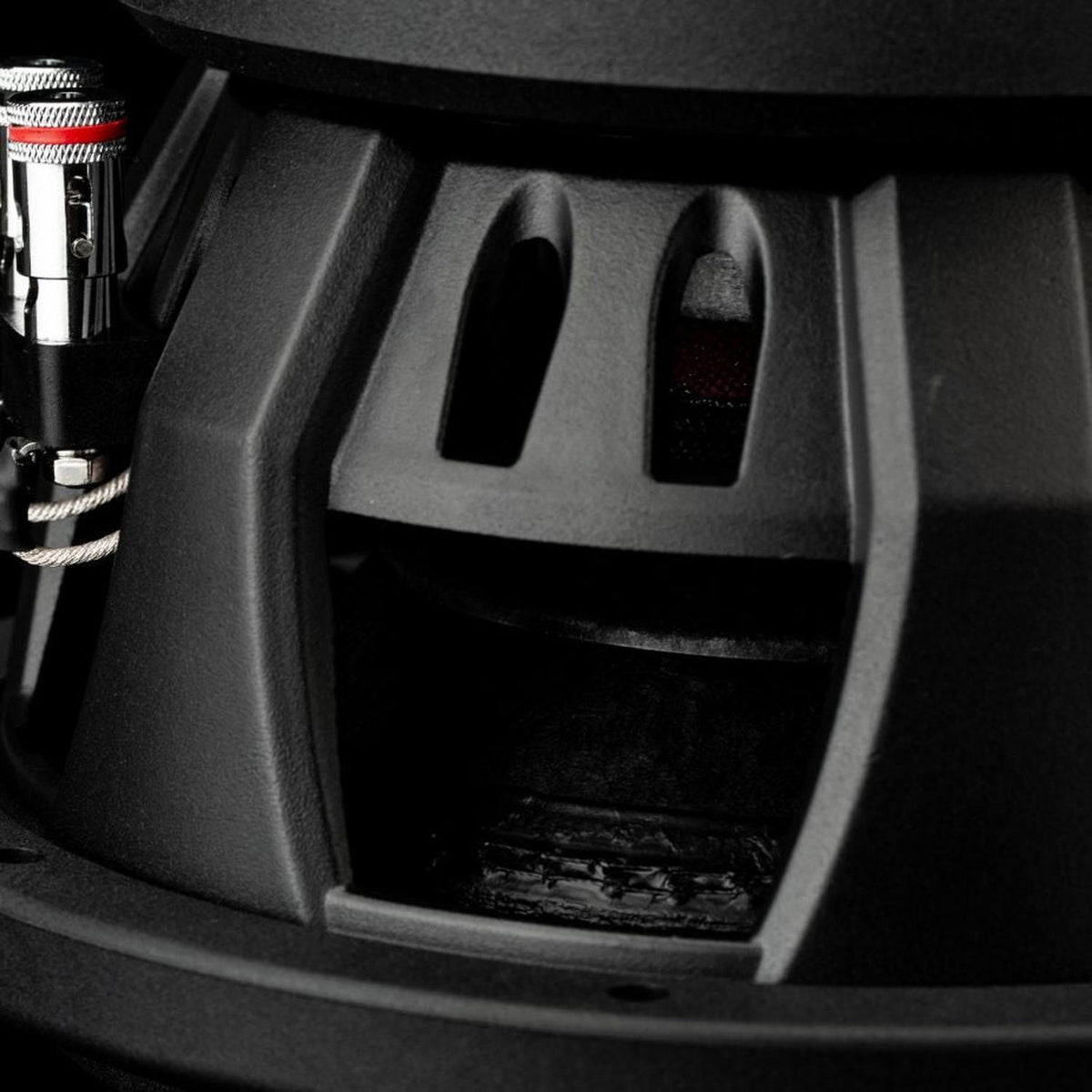Gros plan sur un caisson de basses Gladen Sigma SSWX08, montrant le cadre ventilé et le câblage situé à gauche, destiné au système audio embarqué.