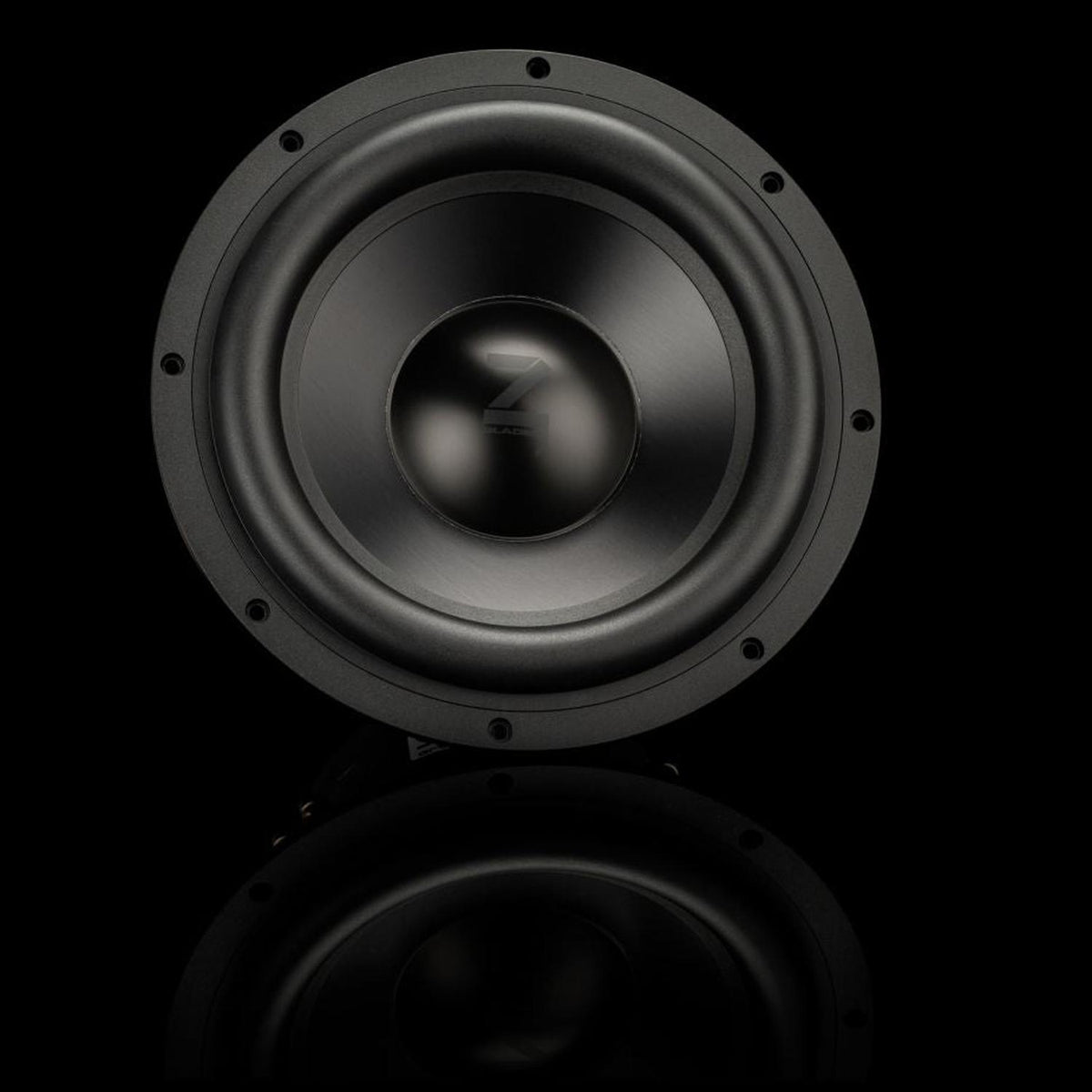 Un caisson de basses Gladen Zeta 10, de couleur noire avec une partie centrale brillante, est présenté sur un fond sombre, mettant en valeur la puissance des basses et laissant entrevoir un léger reflet en dessous.