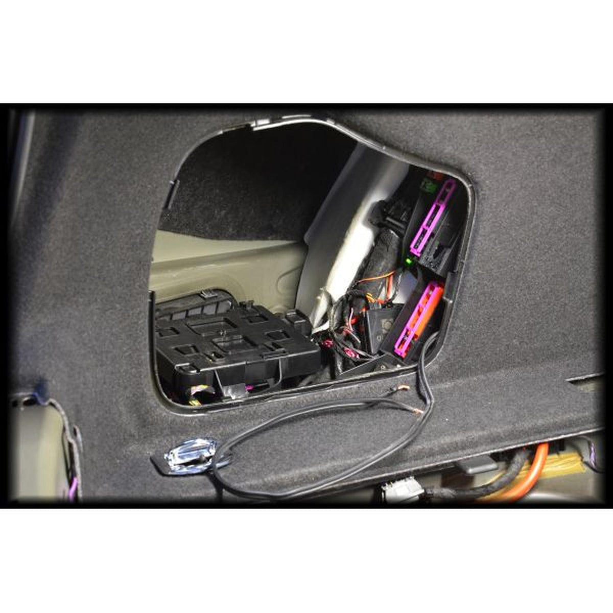 Un primo piano di un pannello aperto dellauto mostra il cablaggio, i fusibili e i componenti dietro le finiture vicino a un subwoofer Masori G10-15 Audi A4 B9 Limousine.