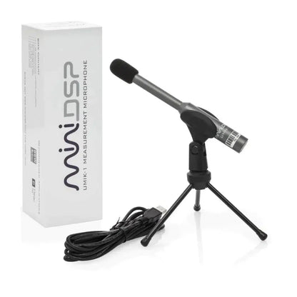 Un micrófono de medición miniDSP UMIK-1 V3, montado en un pequeño trípode y conectado mediante un cable USB, se encuentra junto a una caja blanca con la etiqueta «miniDSP UMIK-1 V3».