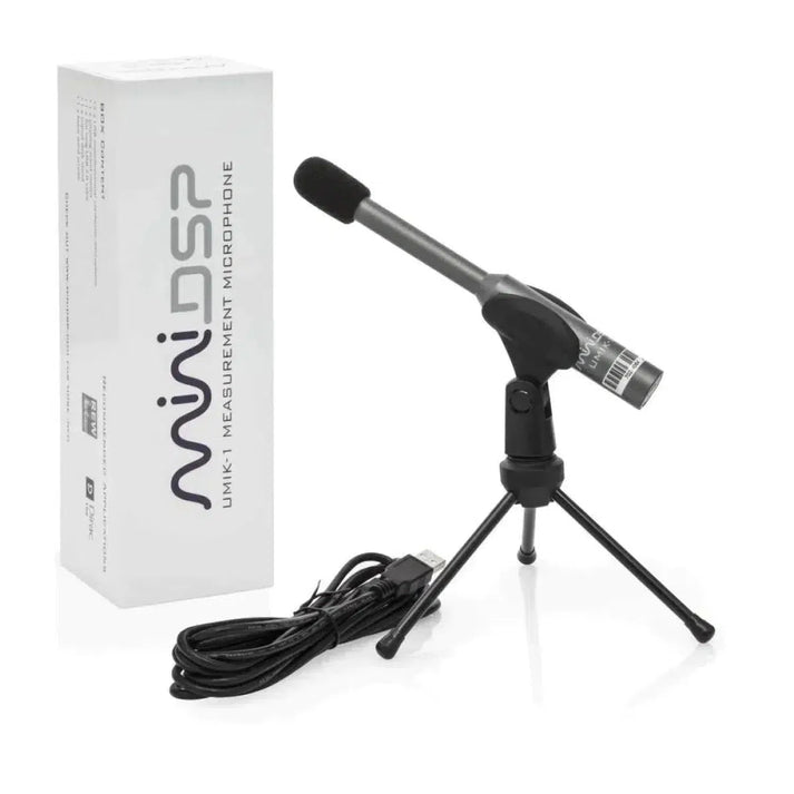 Un micrófono de medición miniDSP UMIK-1 V3, montado en un pequeño trípode y conectado mediante un cable USB, se encuentra junto a una caja blanca con la etiqueta «miniDSP UMIK-1 V3».